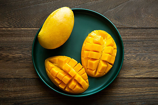 一盘新鲜的芒果被切好放在木板上的盘子里