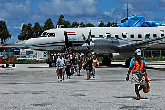 tuvalu,funafuti,crew,walking,on,airfield,by,airplane,with,trees,in,the,background,at,airport