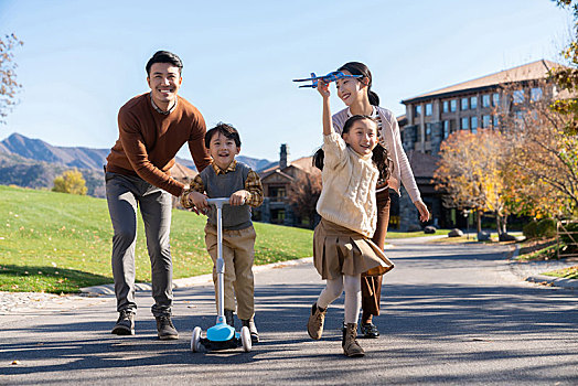 年轻夫妻带着孩子们在玩滑板车