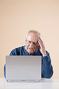 老人,坐,桌子,使用笔记本,电脑,看,迷茫,棚拍,米色背景