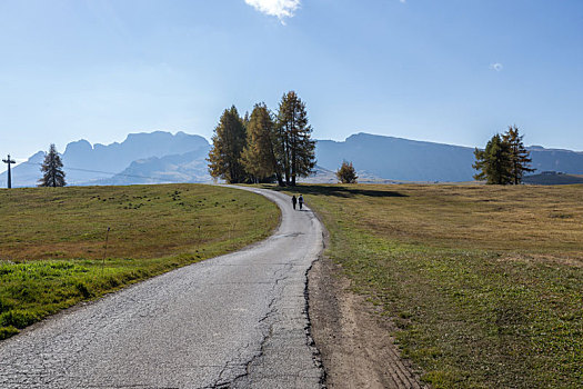 意大利多洛米蒂山脉苏西高原上白天的乡间道路和正在路上徒步的游客