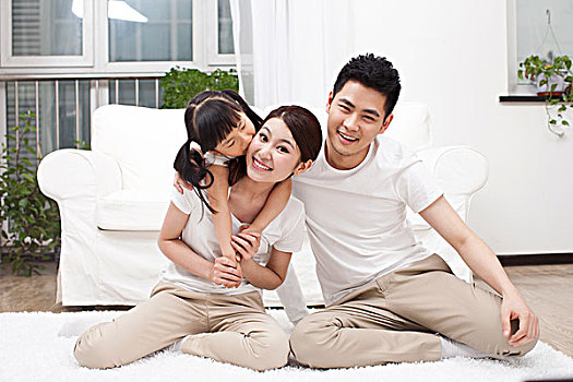 三口之家坐在在白色地毯上快乐合影
