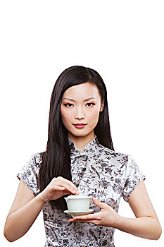 穿旗袍的东方年轻女性拿着一杯茶