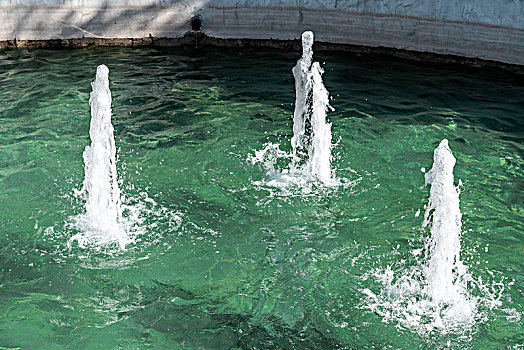 碧绿的水面上有三个喷泉