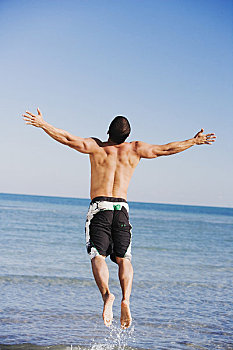 后视图,中年,男人,伸展胳膊,跳跃,海滩