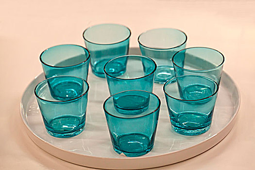 八个透明的蓝色玻璃杯放在一个圆盘中
