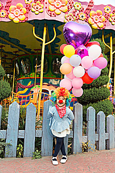 牵气球的小女孩在游乐园扮小丑