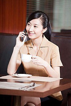 端着咖啡杯的商务女士正在打手机
