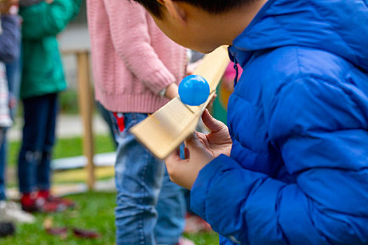 一群小孩在室外公園,玩著传球接龙游戏