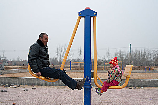 河南伊川县,爷爷和孙女在玩健身器材