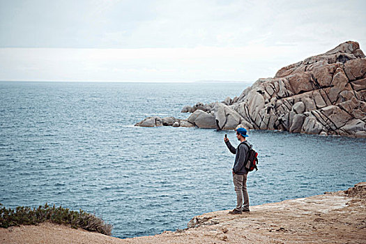 男青年,站立,悬崖,智能手机,摄影,海洋,哥斯达黎加,萨丁尼亚,意大利