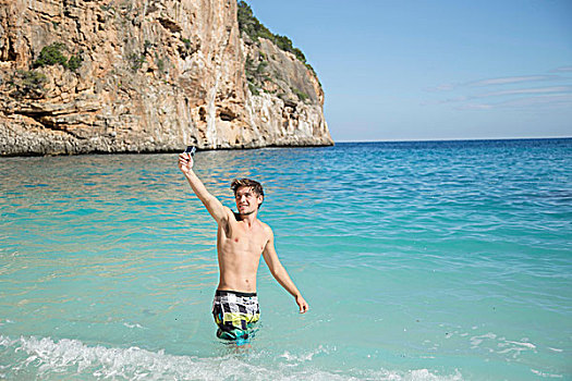 男青年,海洋,抬臂,摄像机,微笑,萨丁尼亚,意大利