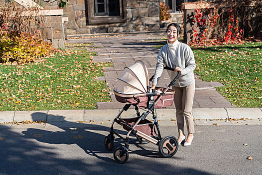 年轻母亲推着婴儿车散步