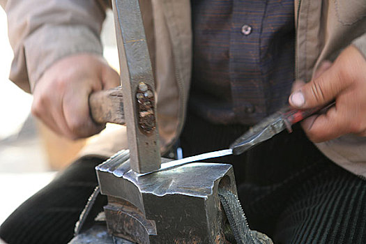 格尔木市区一个用传统方法打制银器的商贩在打制银器