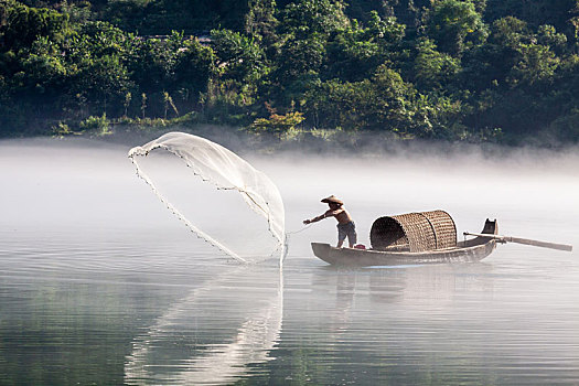 漁夫在飄渺晨霧的湖泊中打魚