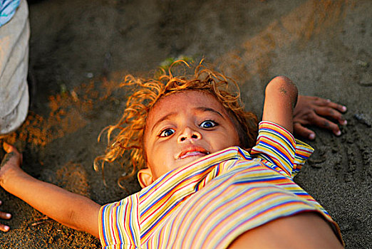 portrait,of,small,dark,skinned,smiling,timorese,blond,boy,with,curly,hair