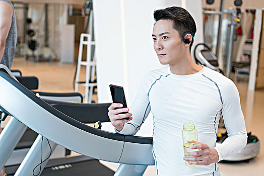 年轻男子在健身房使用手机