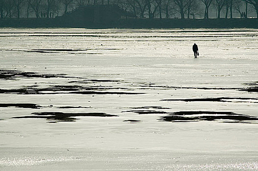 冬季公园内结冰的湖面上走的人