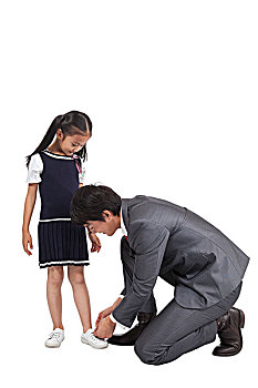 棚拍商务装年轻父亲为穿裙子的小女孩系鞋带