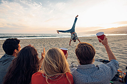 群体,朋友,坐,海滩,看,侧手翻,日落,后视图