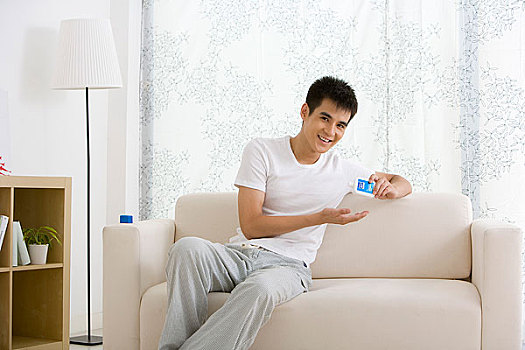 一个年轻的男人坐在家中的沙发上化妆