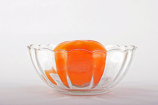 一个透明的玻璃碗里盛着柿子
