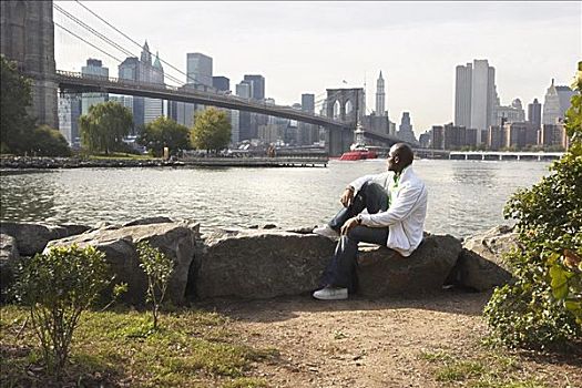男人,坐,岩石上,看,布鲁克林大桥,纽约,美国