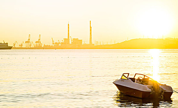 日出时分海面上的快艇与远处的威海码头