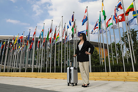 一个手扶行李箱,站在会展中心广场的女商人