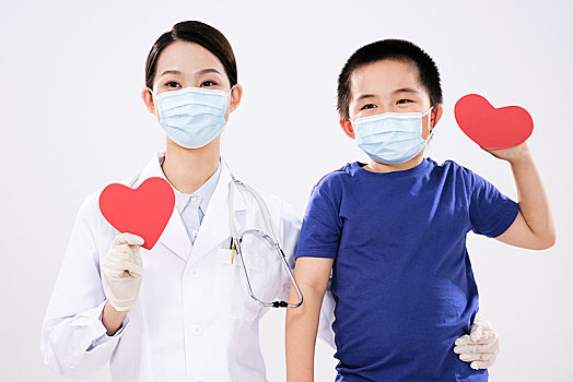 一位女医生和一个小男孩各拿着一颗红心