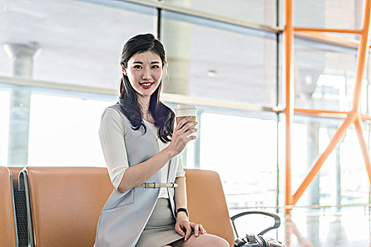 年轻商务女士在机场喝咖啡