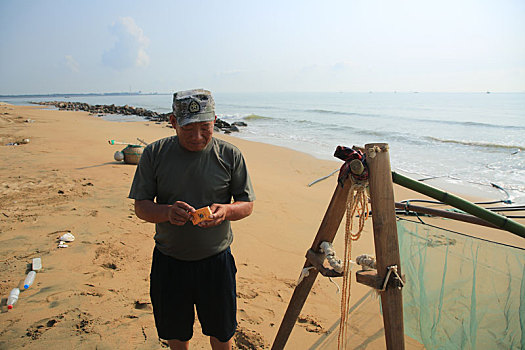 山东省日照市,六旬大叔踩着高跷捞小虾,非遗魅力吸引摄影师海边打卡