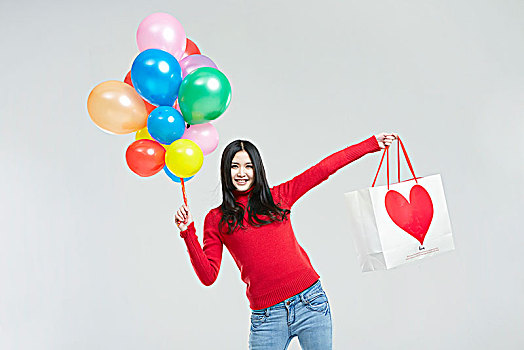 拿气球与购物袋的亚洲女青年