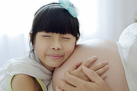 女孩贴在孕妇肚子上感受胎动