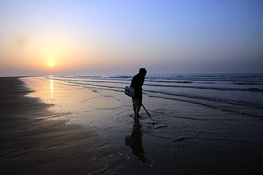 清晨5点的沙滩上,6旬老人扛着锄头淘鲜
