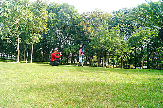 年轻夫妇带着孩子在公园草坪上拍照