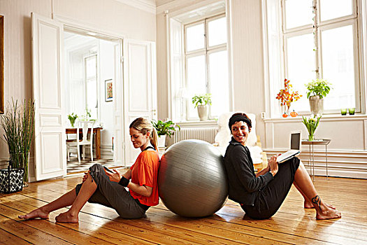 两个女人,坐在地板上,靠着,健身球