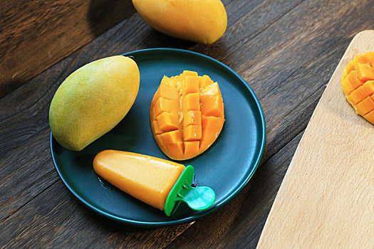 用芒果果泥制作的芒果雪糕和芒果果肉摆放在木桌上