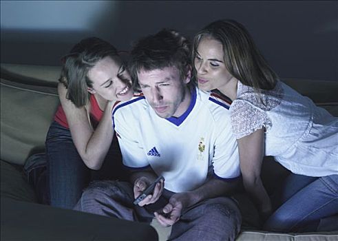 两个女人,一个,男人,坐,沙发,看电视,足球,衬衫