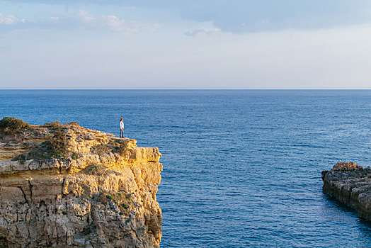 一名亚洲女性站在悬崖边上观赏大海的风景