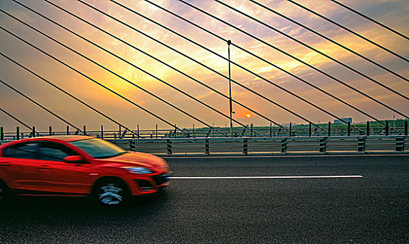 夕阳下的汽车奔跑在大桥上