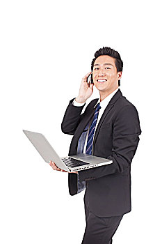 一个使用笔记本电脑打着手机的青年商务男士