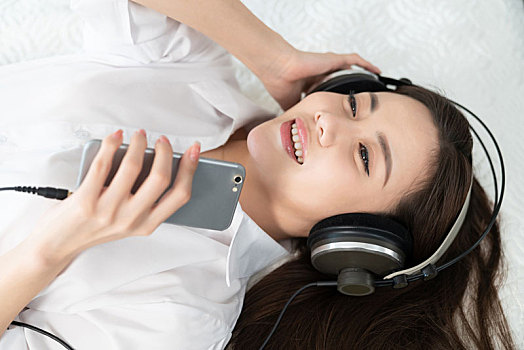 年轻女子躺在床上听音乐