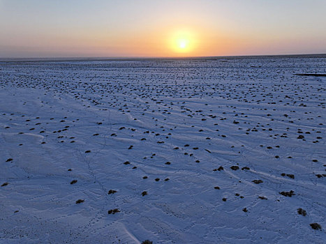 新疆哈密,雪后荒漠和落日余晖相映成景