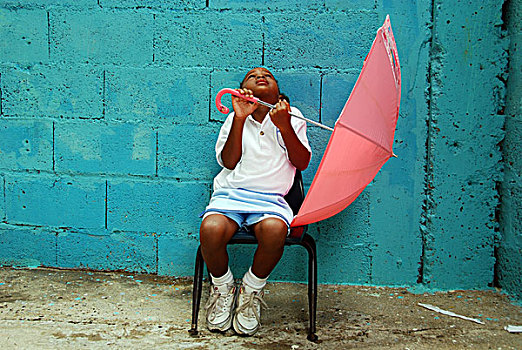 dominica,roseau,preschool,ccf,young,girl,playing,with,pink,umbrella,against,blue,wall