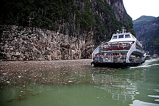 2011年8月7日,前几天三峡库区下大雨产生大量的生活垃圾呈漂浮物堆积在小三峡巴雾峡上游峡谷口,严重影响航道安全,一只小船正忙着打捞这些漂浮物显得力不从心,旅游船只能从漂浮物堆积薄一些的河面上通过