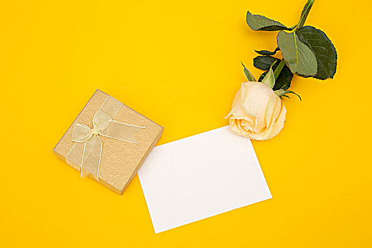 祝福卡片黄色玫瑰喝小礼物在黄色的背景上