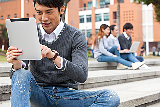 年轻大学生在校园里使用平板电脑