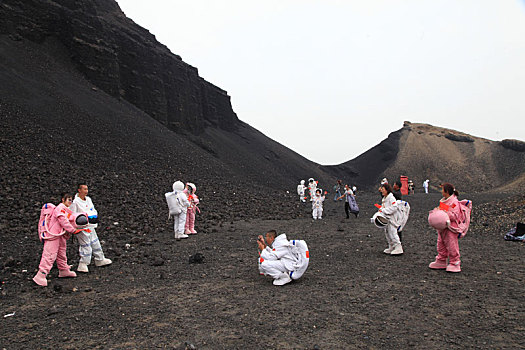 内蒙古火山口游客穿宇航服拿国旗拍照,宛若登陆外星球