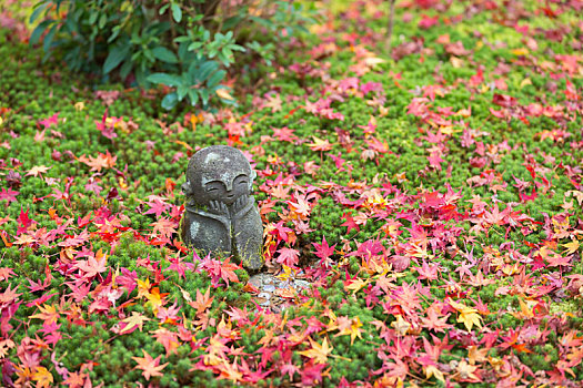 秋季草地上的小地藏石像,京都圆光寺内两只手拖着笑脸的地藏石像